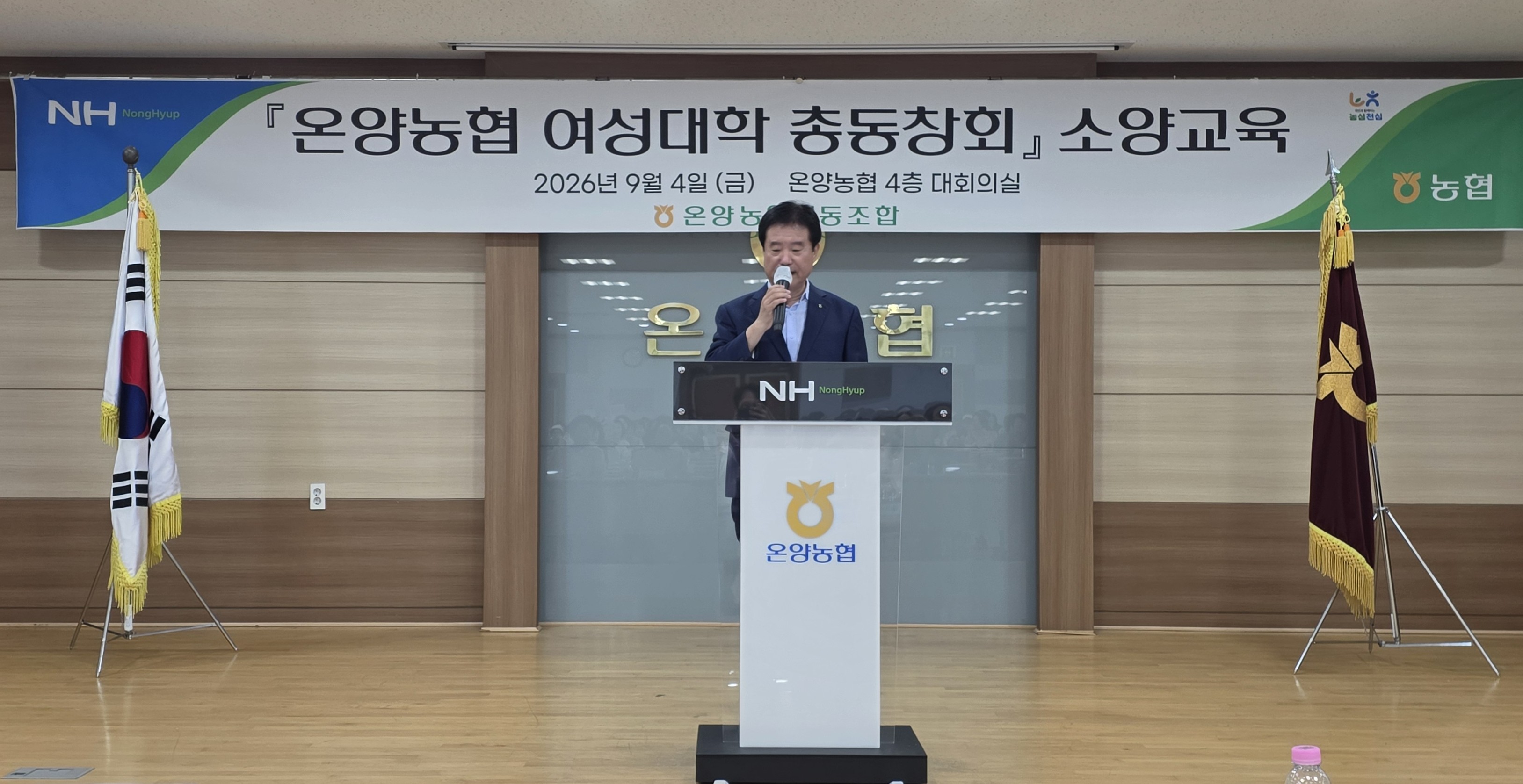 온양농협 여성대학 총동창회 소양교육 현수막 아래 연단에서 마이크를 들고 인사말을 하는 백성현 조합장
