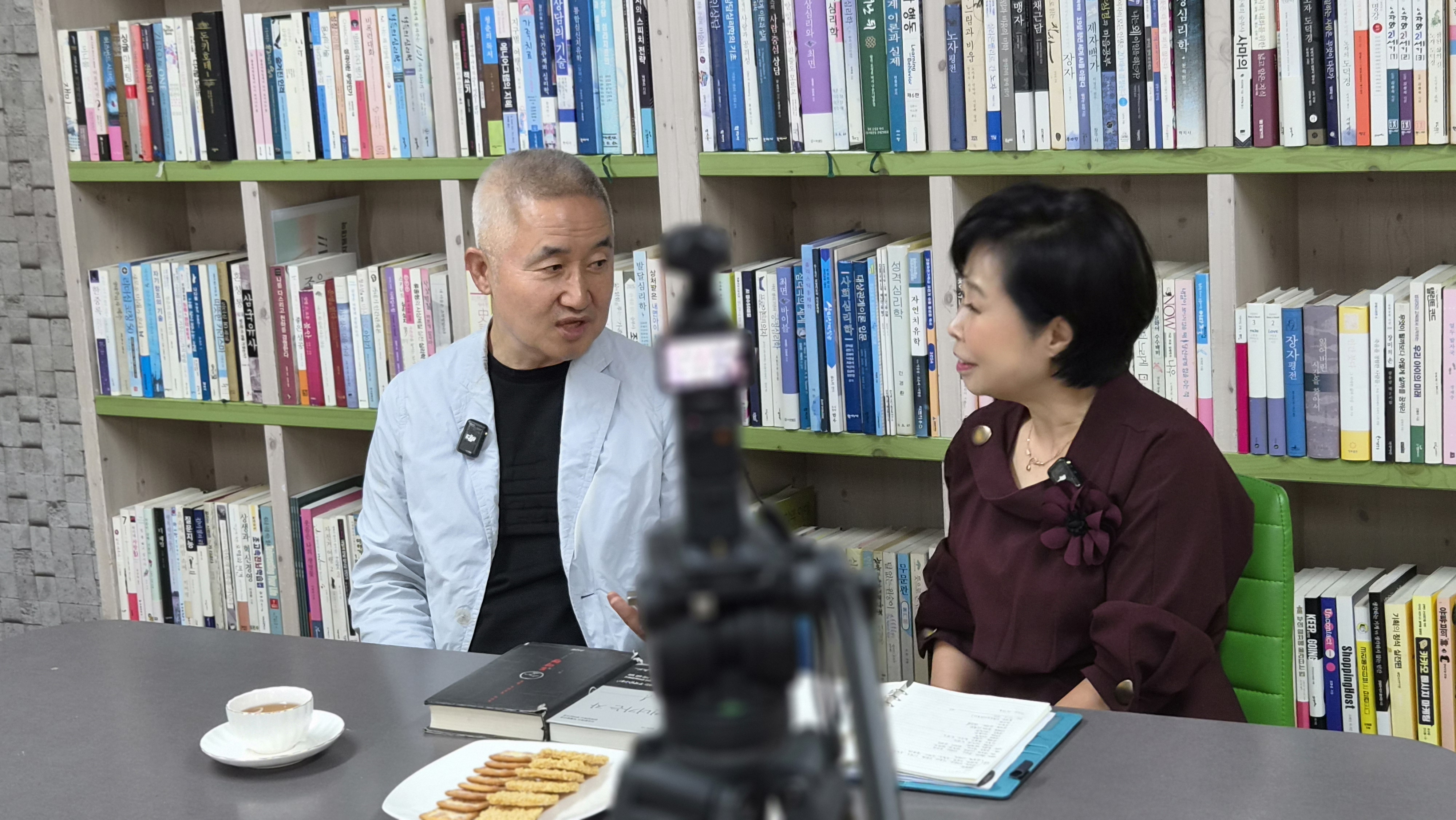 최진석 명예교수와 오행자 교수가 나란히 앉아 대화하는 모습, 탁자 위에 책과 노트