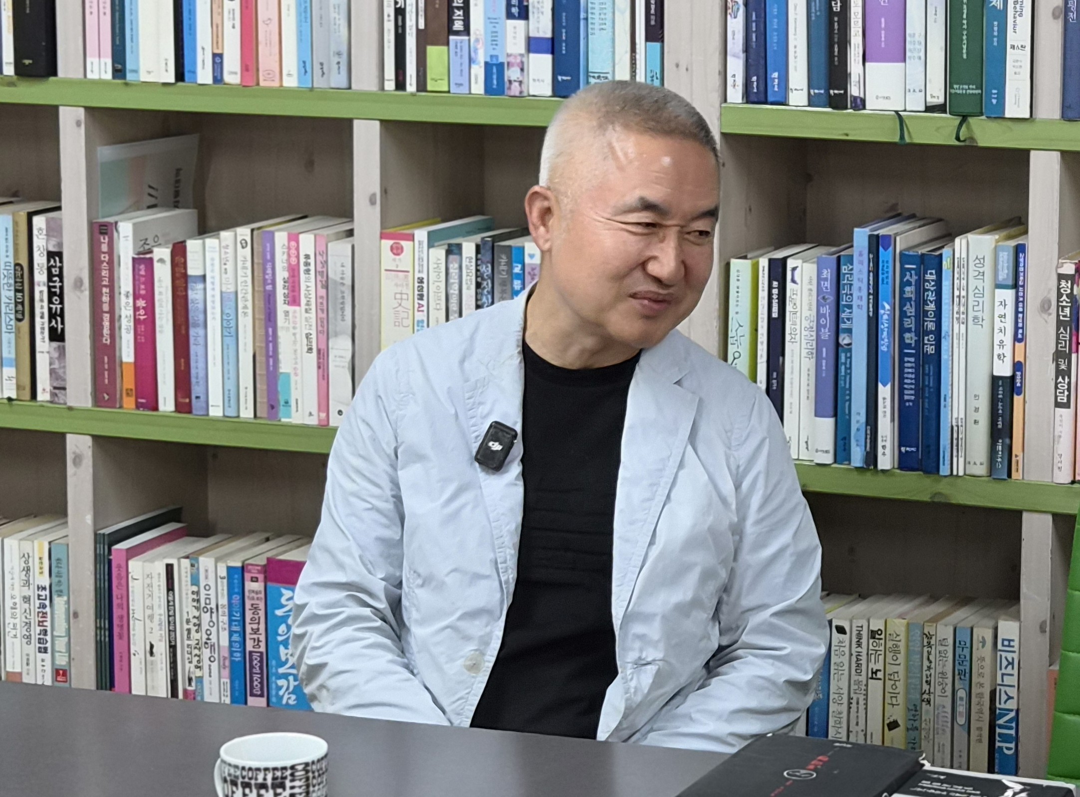책이 빼곡한 서가 앞에 앉아 옆을 바라보며 미소 짓는 최진석 서강대 철학과 명예교수